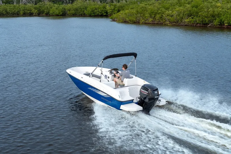 Slide: The Image of 2027 Bayliner 160 Element boat cruising on a calm lake with lush greenery. - 7