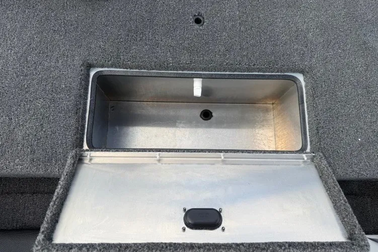 Slide: The Image of Open storage compartment on 2026 Crestliner 1600 Storm boat, featuring a carpeted lid. - 14