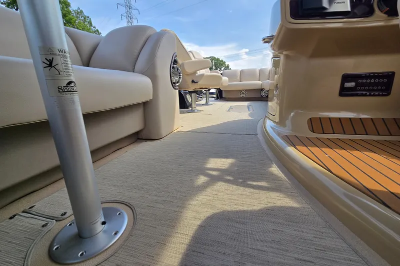 Slide: The Image of Interior view of a 2013 Sanpan 2500 FE pontoon boat with beige seating and flooring. - 24