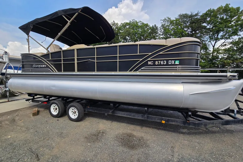 Slide: The Image of 2013 Sanpan 2500 FE pontoon boat on trailer, black canopy, parked outdoors. - 4