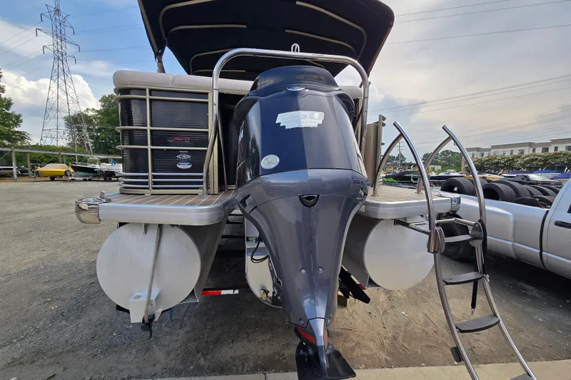 Slide: The Image of 2013 Sanpan 2500 FE pontoon boat with outboard motor and ladder, parked outdoors. - 8