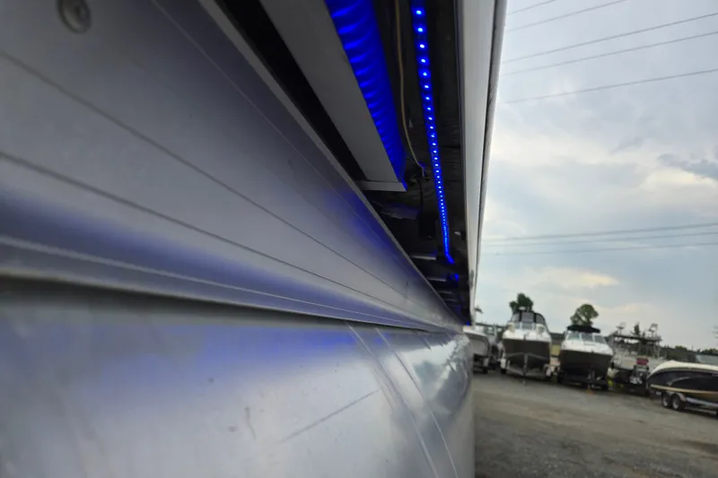 Slide: The Image of Close-up of 2013 Sanpan 2500 FE pontoon boat with blue LED lights, docked outdoors. - 48