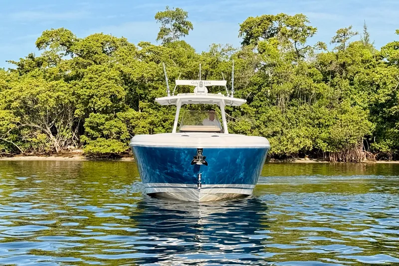Slide: The Image of 2016 Intrepid 375 Center Console boat on calm water, surrounded by lush greenery. - 23