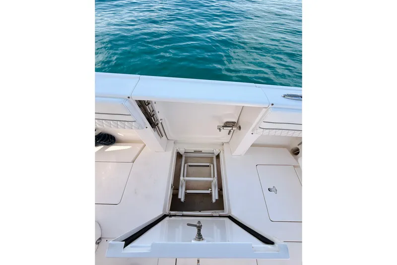 Slide: The Image of 2016 Intrepid 375 Center Console boat with open hatch and ladder, near water. - 75