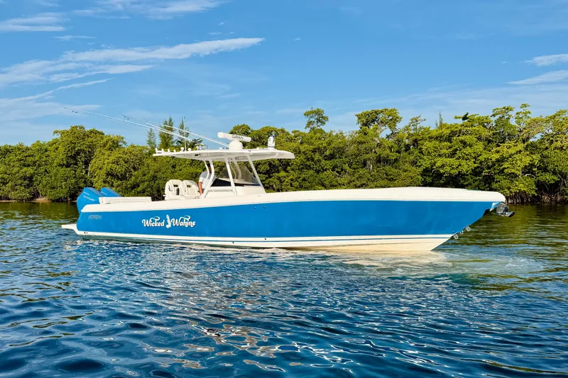 Slide: The Image of 2016 Intrepid 375 Center Console boat cruising on water, surrounded by lush greenery. - 30