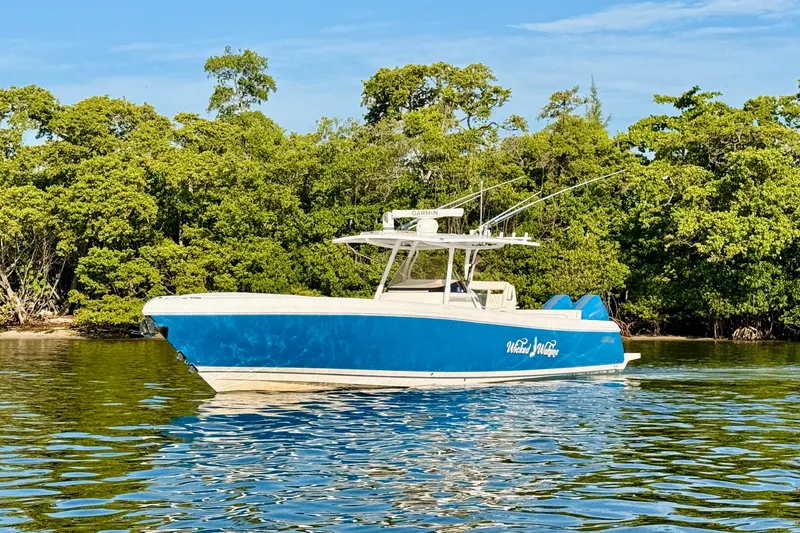 Slide: The Image of 2016 Intrepid 375 Center Console boat on calm water, surrounded by lush greenery. - 25