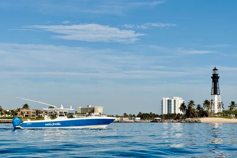Slide: The Image of 2016 Intrepid 375 Center Console boat near a lighthouse and coastal buildings. - 39