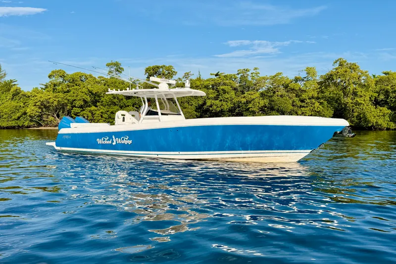 Slide: The Image of 2016 Intrepid 375 Center Console boat on calm water, surrounded by lush greenery. - 31