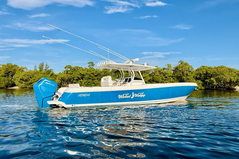 Slide: The Image of 2016 Intrepid 375 Center Console boat on water, blue hull, lush greenery background. - 29