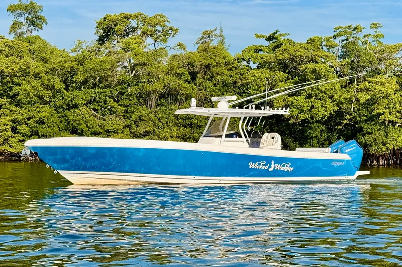 Slide: The Image of 2016 Intrepid 375 Center Console boat on calm water, surrounded by lush greenery. - 27
