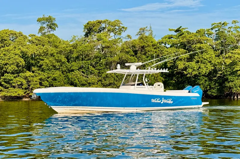 Slide: The Image of 2016 Intrepid 375 Center Console boat on calm water, surrounded by lush greenery. - 26