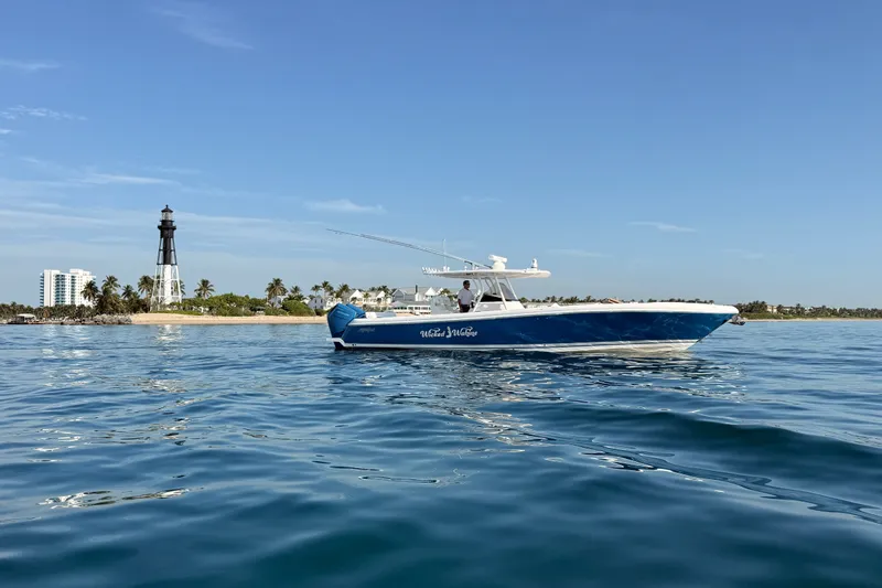 Slide: The Image of 2016 Intrepid 375 Center Console boat on calm waters near a lighthouse and beach. - 36