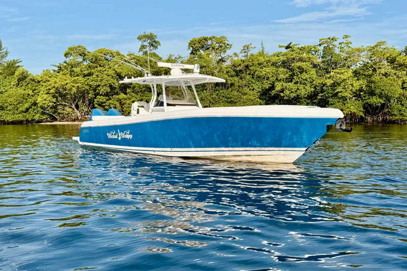 Slide: The Image of 2016 Intrepid 375 Center Console boat on calm water near lush greenery. - 32