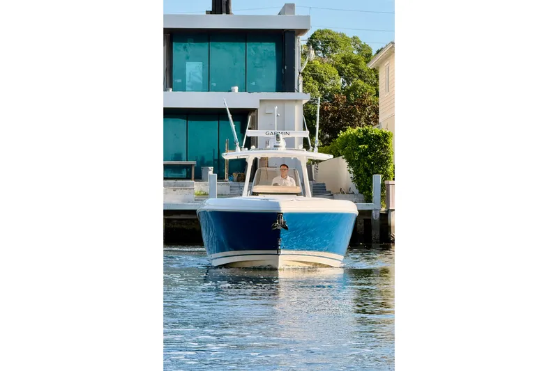 Slide: The Image of 2016 Intrepid 375 Center Console boat on water near modern house. - 22