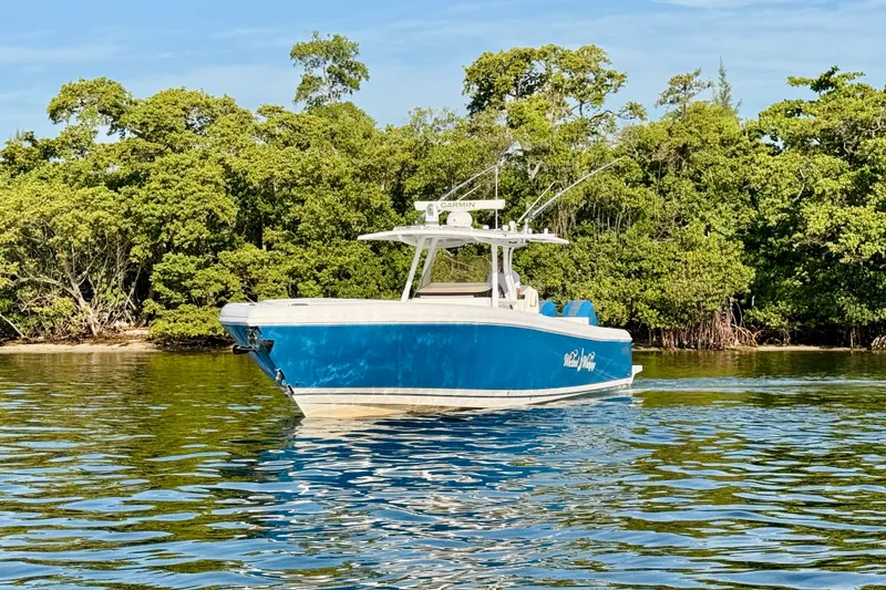 Slide: The Image of 2016 Intrepid 375 Center Console boat on calm water near lush green trees. - 24