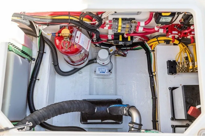 Slide: The Image of The engine compartment of a 2023 Hinckley 35 boat shows wiring, hoses, and a fire extinguisher. - 36
