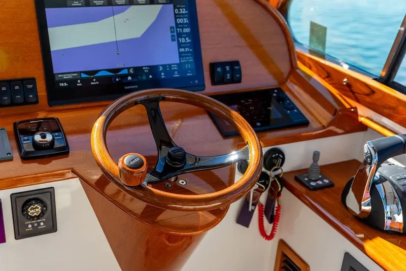 Slide: The Image of Steering wheel and controls of a 2023 Hinckley 35 boat, featuring modern navigation technology. - 20