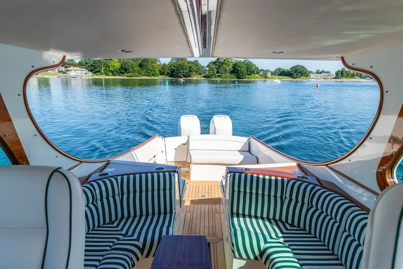 Slide: The Image of Luxury interior of 2023 Hinckley 35 yacht with striped seating, overlooking serene waters. - 24