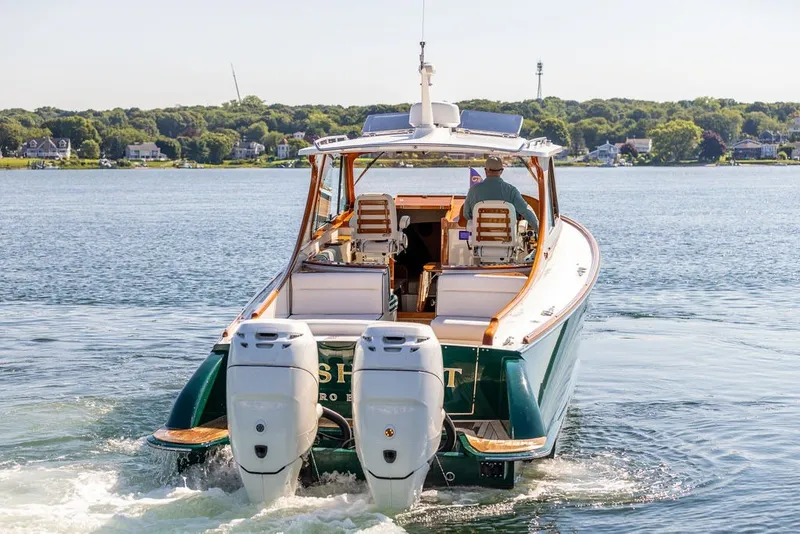Slide: The Image of 2023 Hinckley 35 boat cruising on a scenic lake with dual outboard engines. - 32