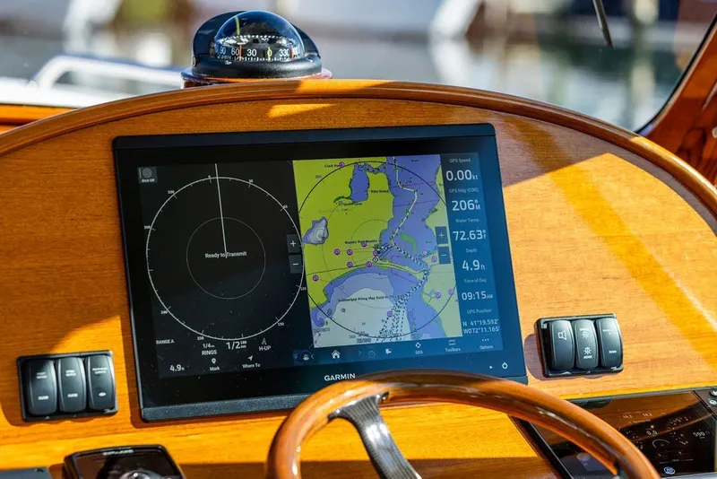 Slide: The Image of Hinckley 35 boat dashboard with Garmin navigation display, compass, and wooden steering wheel, 2023 model. - 21