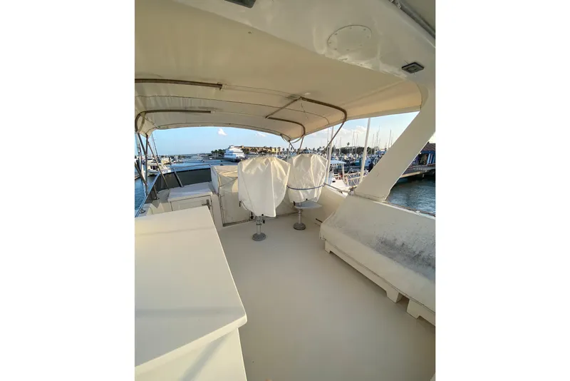 Slide: The Image of 1983 Hatteras 53 Motor Yacht deck with covered seating and marina view. - 55