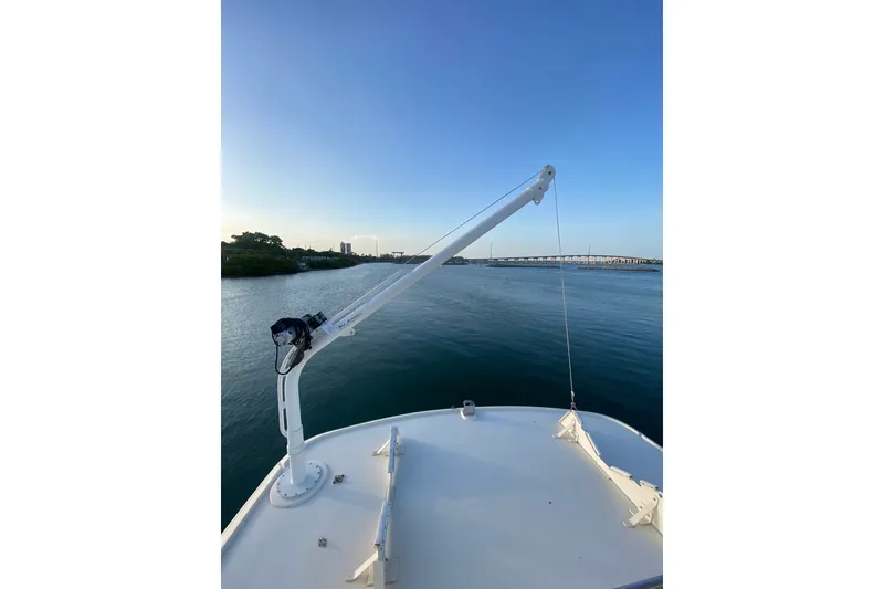 Slide: The Image of Bow view of 1983 Hatteras 53 Motor Yacht with crane, overlooking serene waterway. - 56