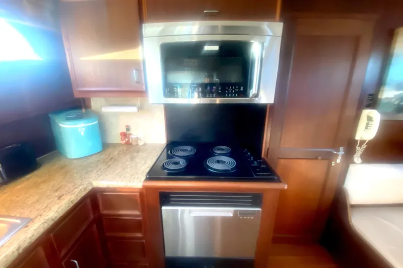 Slide: The Image of 1983 Hatteras 53 Motor Yacht kitchen with stove, microwave, and granite countertop. - 26
