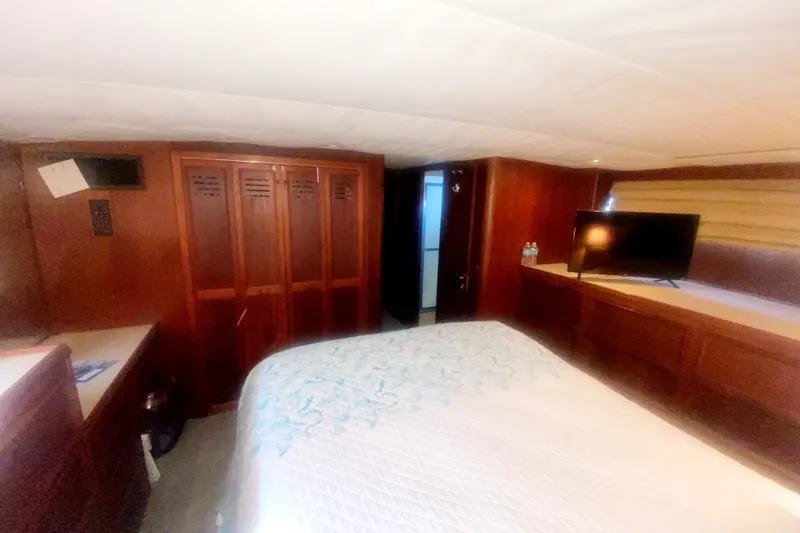 Slide: The Image of Interior of 1983 Hatteras 53 Motor Yacht bedroom with bed, TV, and wooden cabinetry. - 38