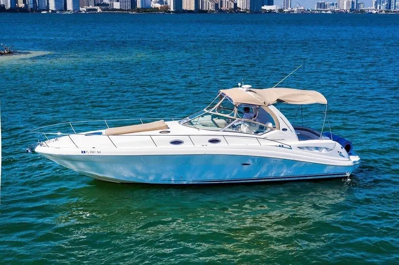 Slide: The Image of 2003 Sea Ray 340 Sundancer yacht cruising on blue waters near city skyline. - 1