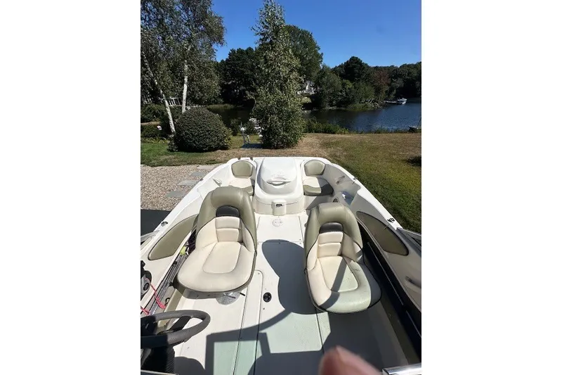 Slide: The Image of 2005 Sea Ray 180 Sport boat interior with seating, near a scenic lakeside view. - 8