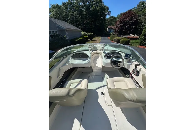 Slide: The Image of 2005 Sea Ray 180 Sport boat interior with steering wheel and seating, parked in driveway. - 5