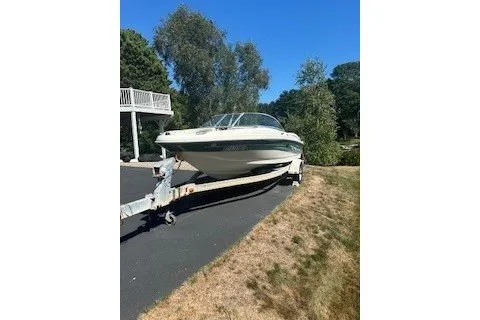 The Image of 2005 Sea Ray 180 Sport boat on trailer, parked on driveway near trees. - 1