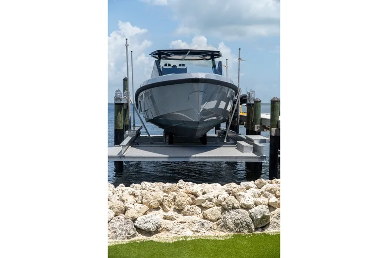 Slide: The Image of 2022 Wally wallytender43X yacht docked on lift, with rocky shoreline and cloudy sky. - 69