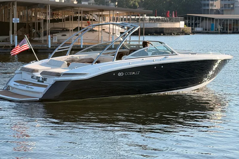 The Image of 2010 Cobalt 296 boat cruising on a calm lake near a marina. - 0