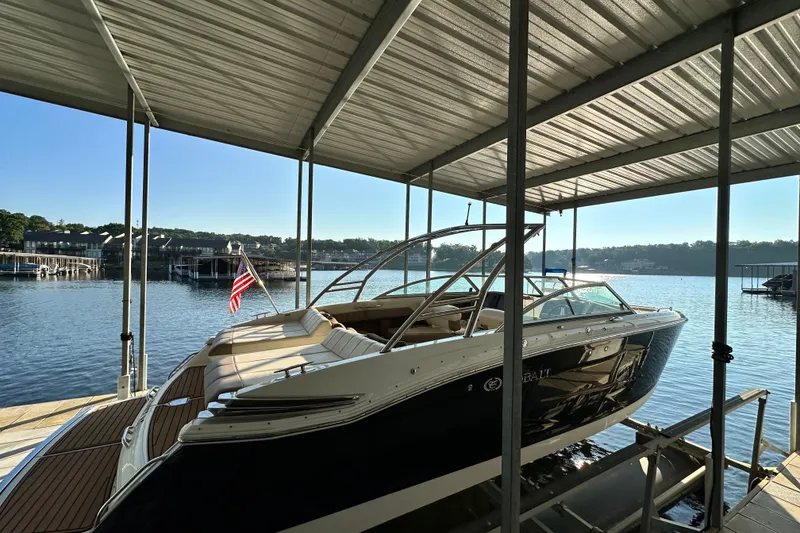 Slide: The Image of 2010 Cobalt 296 boat docked under a covered marina with scenic lake view. - 5