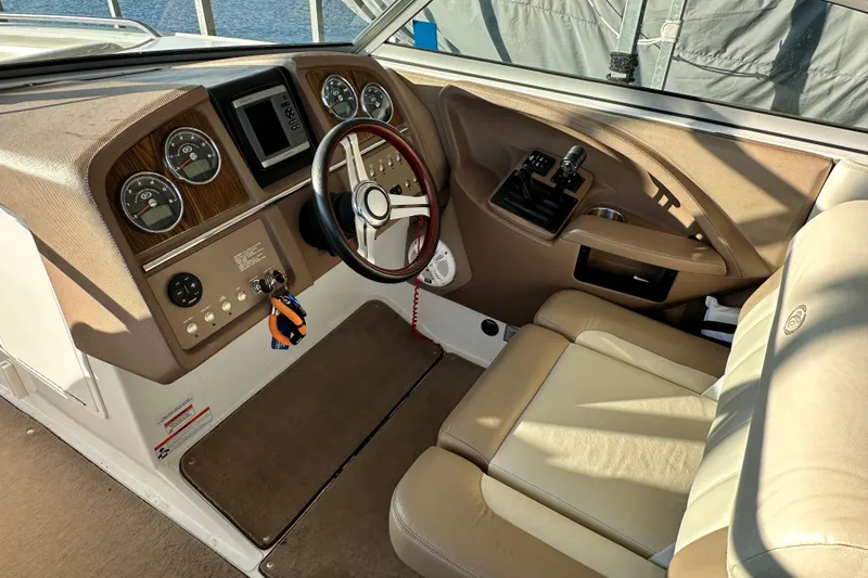 Slide: The Image of 2010 Cobalt 296 boat cockpit with steering wheel, gauges, and beige seating. - 14