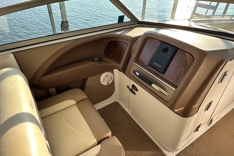 Slide: The Image of Interior of a 2010 Cobalt 296 boat, featuring beige seating and wood-accented dashboard. - 12