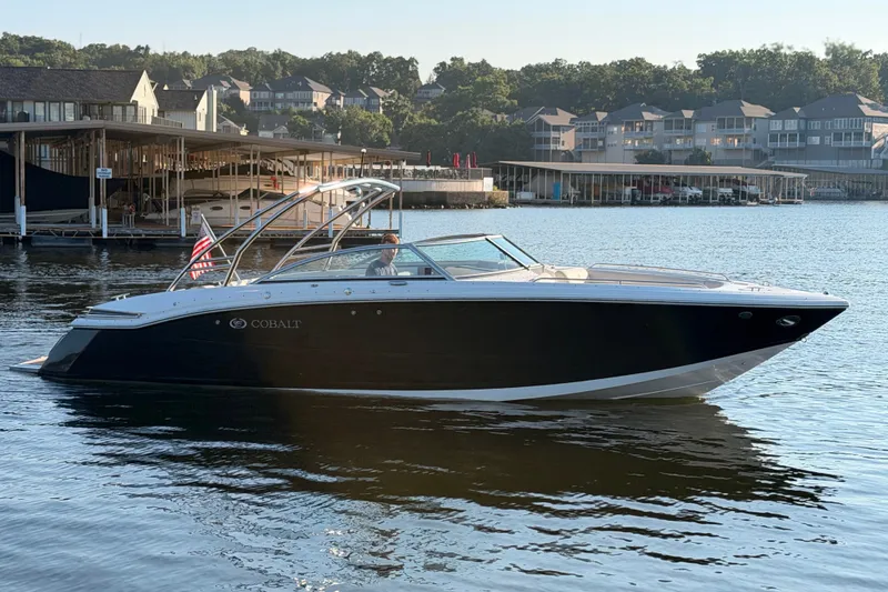 Slide: The Image of 2010 Cobalt 296 boat on calm water near marina, with American flag. - 1