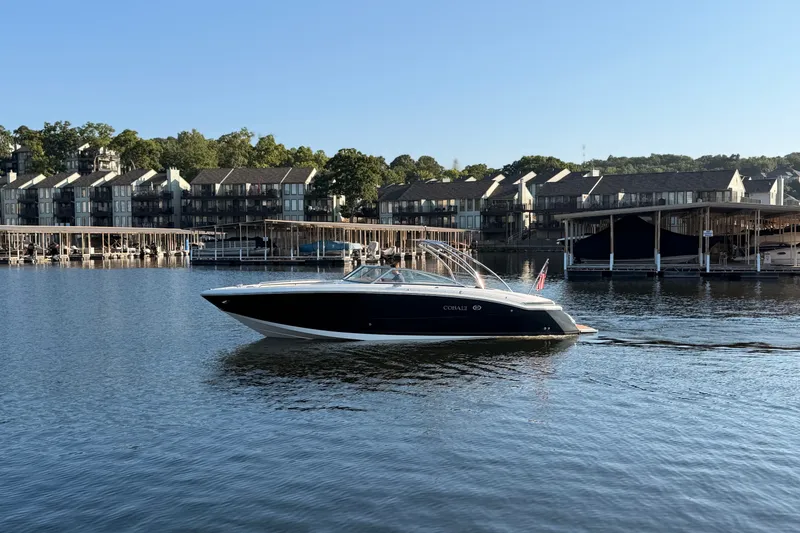 Slide: The Image of 2010 Cobalt 296 boat cruising on a serene lake near waterfront homes. - 25