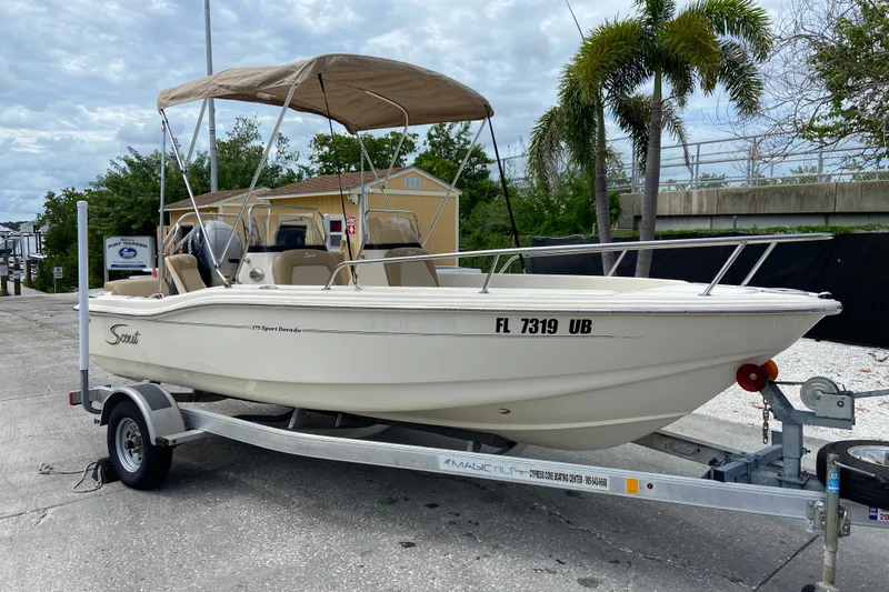 The Image of 2021 Scout 175 Sport Dorado boat on trailer with canopy, parked near palm trees. - 0