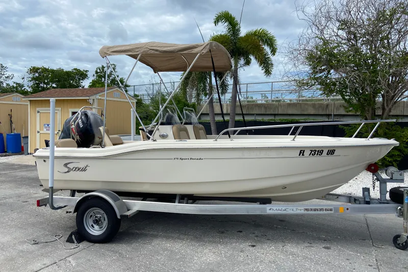Slide: The Image of 2021 Scout 175 Sport Dorado boat on trailer with canopy, parked outdoors. - 1