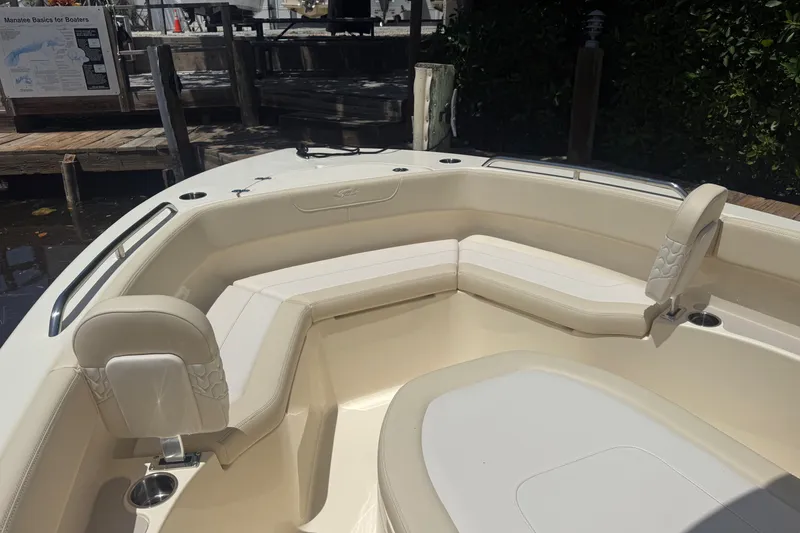 Slide: The Image of 2027 Scout 220 XSF boat interior with beige seating and cup holders at dock. - 15