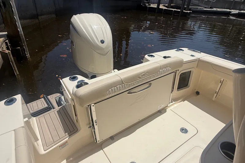Slide: The Image of 2027 Scout 220 XSF boat interior with outboard motor, docked in calm water. - 10