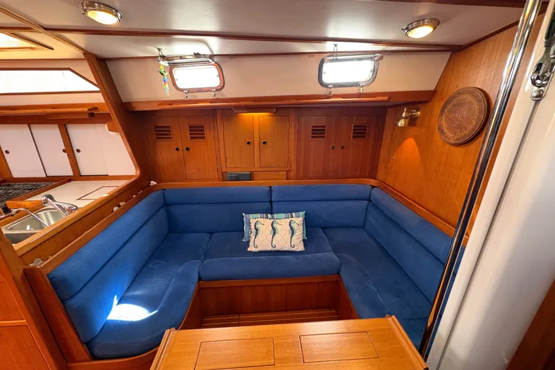 Slide: The Image of Cozy 1989 Cambria 44/46 yacht interior with blue seating and wooden cabinetry. - 19
