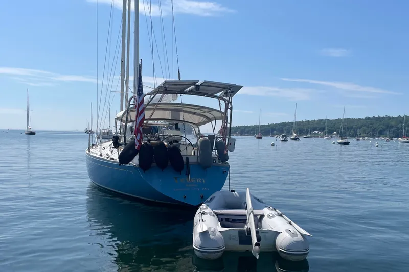 Slide: The Image of Sailboat Cambria 44/46 (1989) anchored with dinghy, calm waters, clear sky. - 4