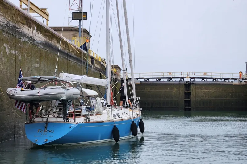 Slide: The Image of Sailboat "Cambria 46" from 1989 in a lock, with dinghy and American flag. - 6