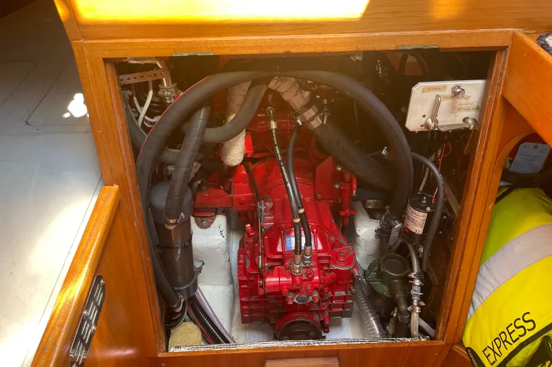 Slide: The Image of Engine compartment of a 1989 Cambria 44/46 sailboat, featuring a red engine and various hoses. - 32