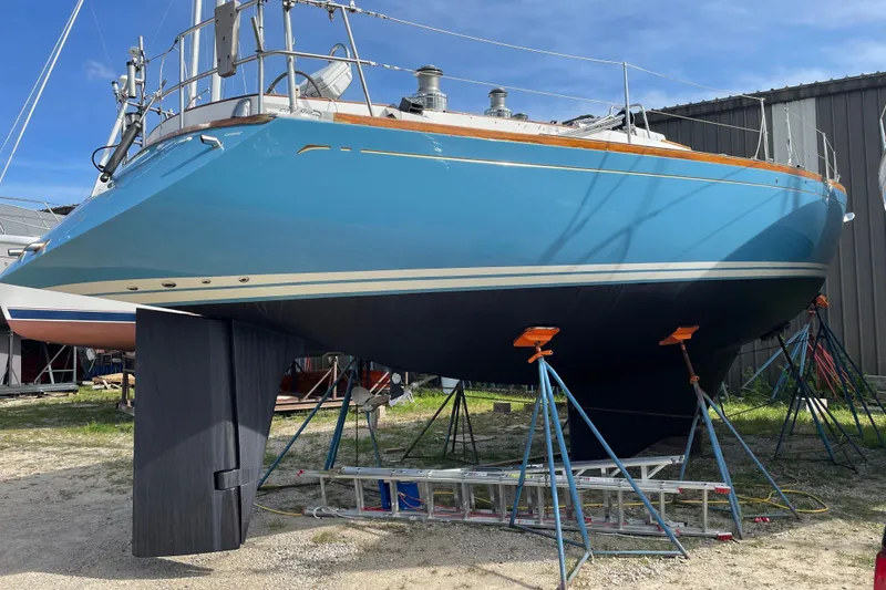Slide: The Image of Blue 1989 Cambria 46 sailboat on stands in a boatyard under clear sky. - 36