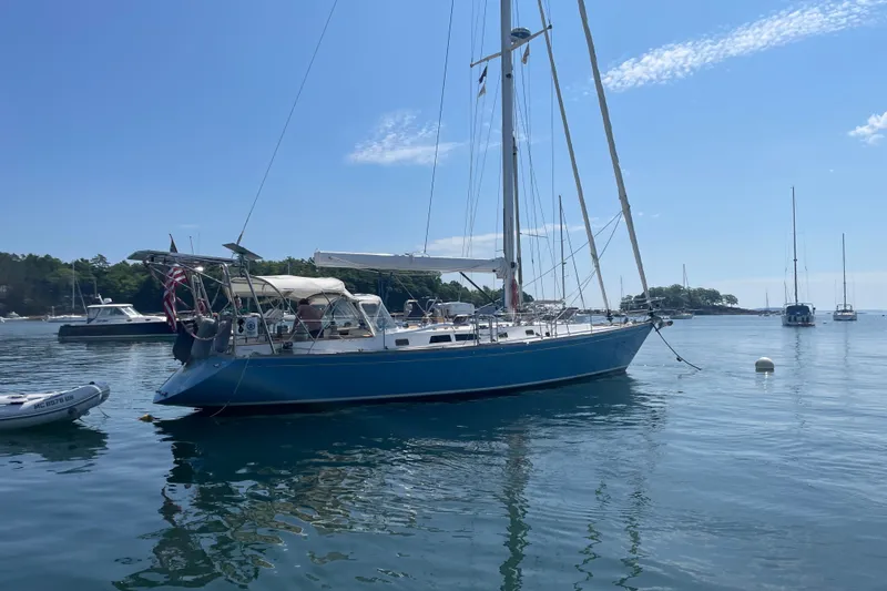 Slide: The Image of 1989 Cambria 44/46 sailboat anchored in a serene harbor with clear blue skies. - 11