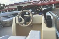 Slide: The Image of 2017 SMOKERCRAFT boat interior with steering wheel and controls, docked near a marina. - 11